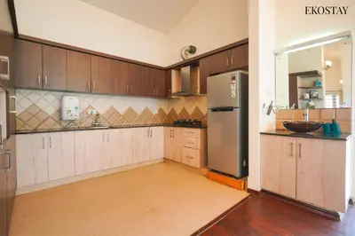 a kitchen with wooden cabinets and a stainless steel refrigerator at EKOSTAY - Skyfall Elysium Villa in Ooty