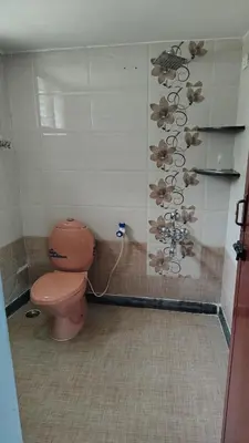 a bathroom with a pink toilet and flowers on the wall at Pine Stay in Alāndurai