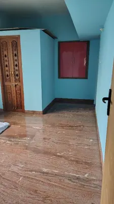 an empty room with blue walls and wooden floors at Pine Stay in Alāndurai