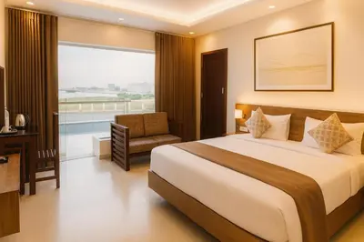 a bedroom with a bed and a chair and a window at Aura Airport Hotel in Nedumbassery
