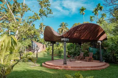 a wooden pavilion in a garden with chairs on it at Madilina Cottage in Parūr