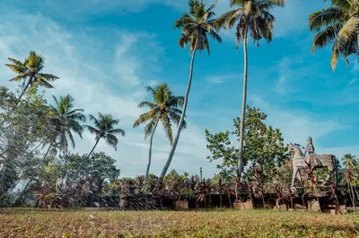 a statue of two horses in a field with palm trees at Madilina Cottage in Parūr