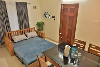 a room with a bed and a table and a door at Prithvi Nila Heavens 3 BHK Homestay Ground Floor in Guruvāyūr