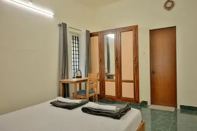 a bedroom with a bed and a desk and a table at Prithvi Nila Heavens 3 BHK Homestay Ground Floor in Guruvāyūr