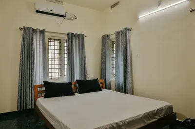 a bedroom with a bed in a room with windows at Akasha Nila Heavens 2 BHK Homestay - Top floor in Guruvāyūr