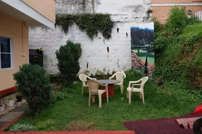 a patio with a table and chairs in the grass at Winterfell Park in Ooty