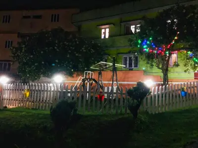 a white fence in front of a house with christmas lights at Winterfell Park in Ooty