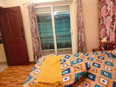 a bed with a quilt on it in a room with a window at AAK Hills stay villa in Kodaikānāl