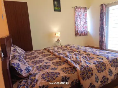 a bedroom with a bed with a comforter and a window at AAK Hills stay villa in Kodaikānāl