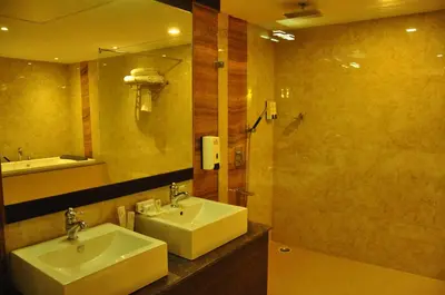 a bathroom with a sink and a mirror and a shower at Hotel Atrium in Erode
