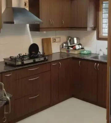 a kitchen with wooden cabinets and a stove top oven at Puthooram Veedu in Chakkarakkal