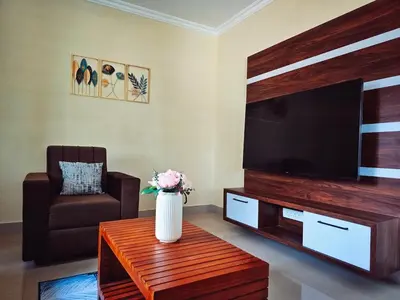 a living room with a television and a vase of flowers on a table at Tranquil Nest Villa - 4BHK Villa - Entire Villa stay in Wayanad in Kalpetta