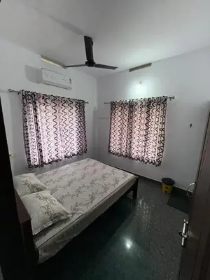 a bedroom with a bed and two windows at Anchery homes in Trichūr