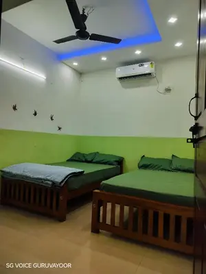 two beds in a room with a ceiling fan at Clap House Home in Guruvāyūr