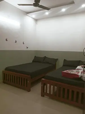two beds in a room with a ceiling at Clap House Home in Guruvāyūr