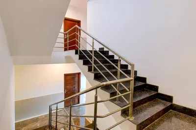 a staircase in a house with a metal railing at Super Townhouse Oak Sri Mahadeshwara Convention Centre Formerly Shri Aprameya Resort in Mysore
