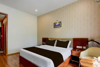 a bedroom with a bed and a table and a chair at Super Townhouse Oak Sri Mahadeshwara Convention Centre Formerly Shri Aprameya Resort in Mysore