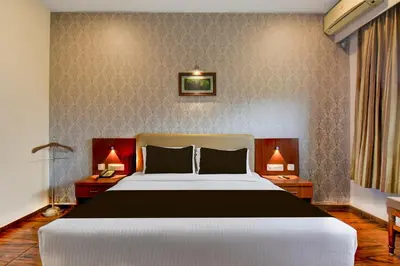 a bedroom with a large bed and two lamps at Super Townhouse Oak Sri Mahadeshwara Convention Centre Formerly Shri Aprameya Resort in Mysore