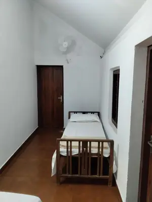 a bedroom with a bed in a white room at Pariyarathu veedu, 4 Bed Hostel in Wayanad