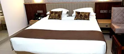 a large white bed in a hotel room at Hotel Queen Maria in Kizhillam