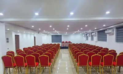 a room filled with red chairs in a hall at Hotel Queen Maria in Kizhillam