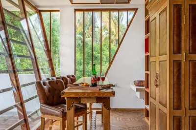 a room with a table and chairs and windows at Punya Farms - Luxury 5BR near Isha Yoga in Alāndurai