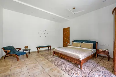 a bedroom with a bed and a table and a chair at Punya Farms - Luxury 5BR near Isha Yoga in Alāndurai