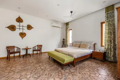 a bedroom with a bed and a table and chairs at Punya Farms - Luxury 5BR near Isha Yoga in Alāndurai