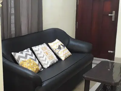 a black leather couch with three pillows on it at Peaceful Vacation Home Near the City in Cochin