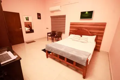 a bedroom with a bed and a table and chairs at Sreedevi Gardens in Irikkūr