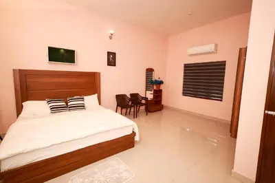 a bedroom with a bed and a table and chairs at Sreedevi Gardens in Irikkūr