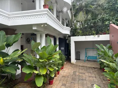 a courtyard of a house with plants and a blue bench at Sreedevi Gardens in Irikkūr