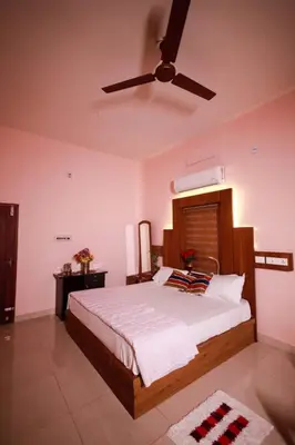 a bedroom with a bed with a ceiling fan at Sreedevi Gardens in Irikkūr