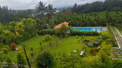 an aerial view of a garden with a swimming pool at Coorg Riverness Resort in Kushālnagar