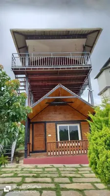 a house with a balcony on top of it at Coorg Riverness Resort in Kushālnagar