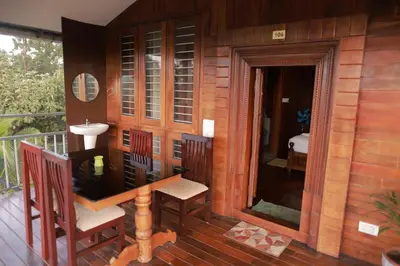 a wooden house with a sink and chairs on a balcony at Coorg Riverness Resort in Kushālnagar