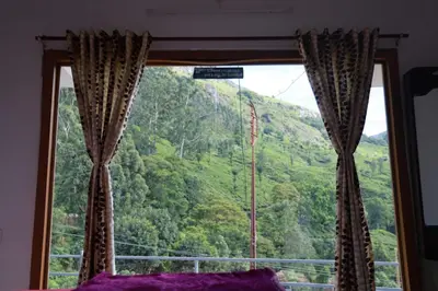 a bedroom window with a view of a mountain at Munnar Mountain view cottage in Munnar