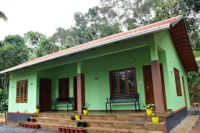 a green house with a bench on the porch at Samuals Villa Wayanad in Mānantoddy