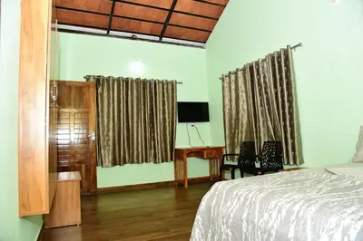 a bedroom with a bed and a desk and curtains at Samuals Villa Wayanad in Mānantoddy
