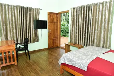 a bedroom with a bed and a desk and a television at Samuals Villa Wayanad in Mānantoddy