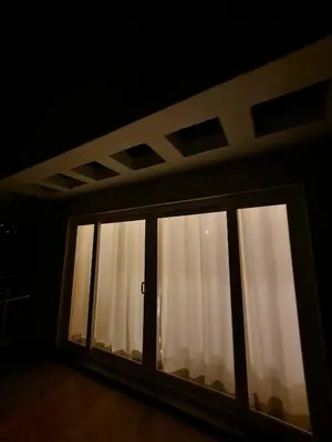 a window with white curtains in a dark room at The Ark Haven Ooty by Scenic Serenity Stays in Ketti
