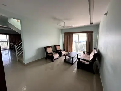 a living room with three chairs and a table at Ocean View 4 BHK Apartment in Kannur