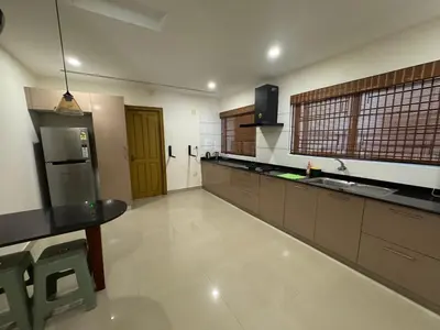 a large kitchen with a table and a refrigerator at Ocean View 4 BHK Apartment in Kannur