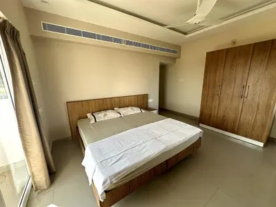 a bedroom with a large bed and a wooden cabinet at Ocean View 4 BHK Apartment in Kannur