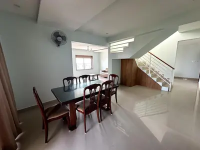 a dining room with a table and chairs and a staircase at Ocean View 4 BHK Apartment in Kannur