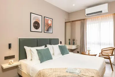 a bedroom with a large white bed with a green headboard at Altin Stays in Coimbatore