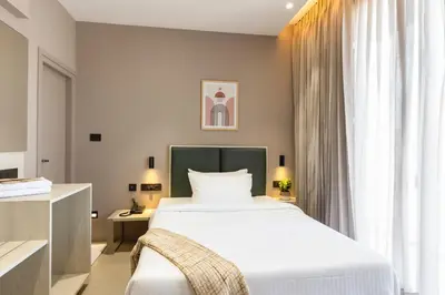 a bedroom with a large white bed and a window at Altin Stays in Coimbatore