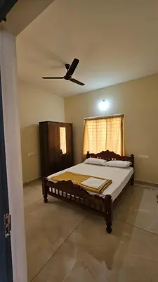 a bedroom with a large bed with a ceiling fan at NAMERA Serviced Apartments in Gonikoppal