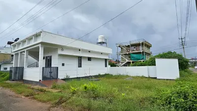 a white house and a building with a water tower at NAMERA Serviced Apartments in Gonikoppal
