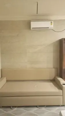 a room with a couch with a air conditioner on the wall at Hotel Maharajas in Kāmānayakkanpālaiyam